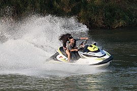 Couple of teenagers riding a jestski splashing on the Mekong in Laos.jpg